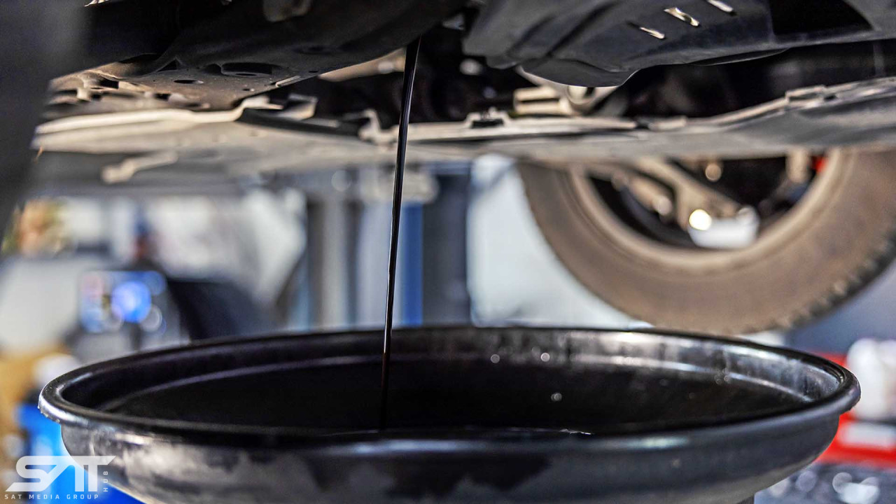 Cropped and close up picture of oil draining from the car engine at mechanic's shop.